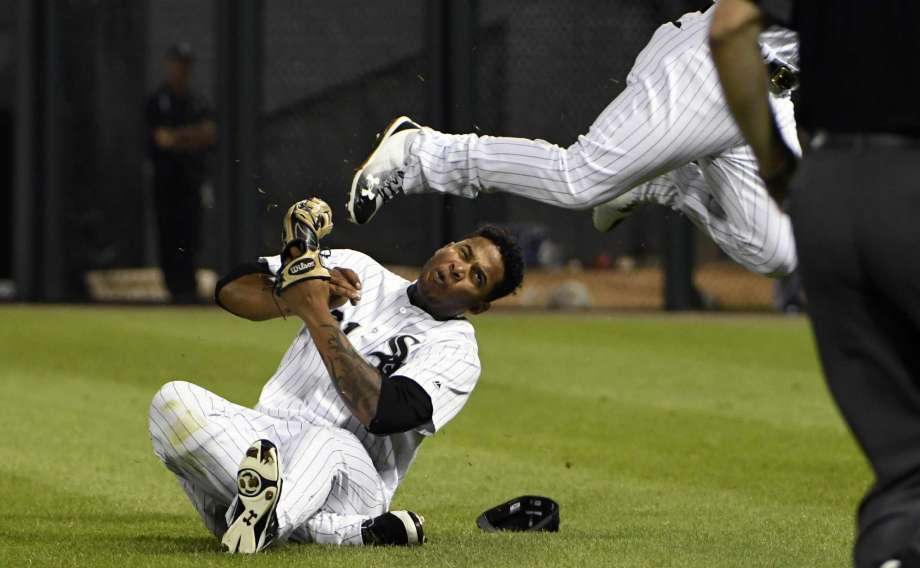 El jugador de los Medias Blancas, Willy García, en el suelo, es golpeado en la cabeza por la rodilla de su compañero Yoan Moncada, centro, durante un partido contra los Azulejos de Toronto el lunes, 31 de julio de 2017, en Chicago.