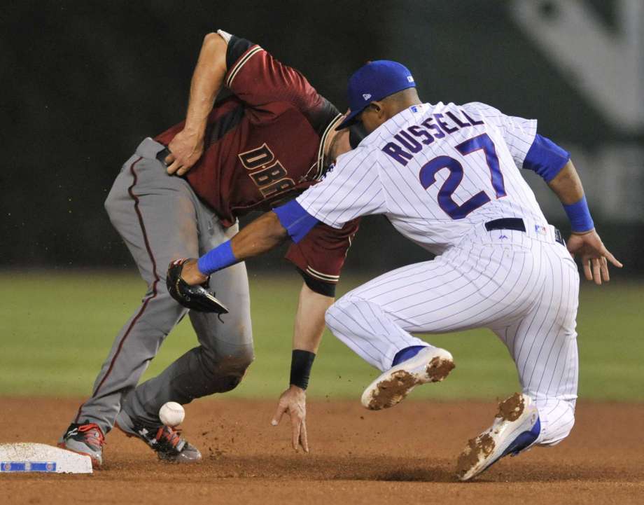 El jugador de los Cachorros, Addison Russell, derecha, suelta la pelota al tratar de sacar de out a A.J. Pollack en un partido el miércoles, 2 de agosto de 2017, en Chicago