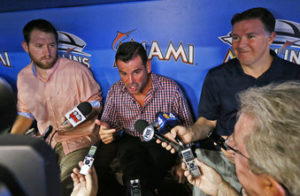 El presidente de los Marlins de Miami, David Samson (centro), habla con la prensa antes de un encuentro ante los Rockies de Colorado, el sábado 12 de agosto de 2017