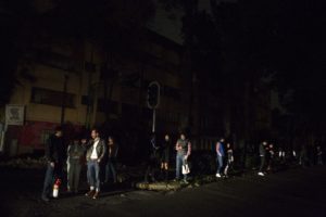 People who evacuated from bars during an earthquake stand in the street in La Roma neighborhood of Mexico City, sections of which lost power, just before midnight on Thursday, Sept. 7, 2017. A massive earthquake hit off the coast of southern Mexico late Thursday night, causing buildings to sway violently and people to flee into o the streets in panic as far away as the capital city. (AP Photo/Rebecca Blackwell)