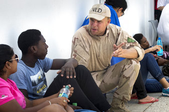 En esta foto distribuida por el ministerio de Defensa de Holanda, un soldado habla con habitantes de la parte holandesa de San Martín, una isla del Caribe que comparte con Francia, tras el paso del huracán Irma, 11 de septiembre de 2017. El rey Guillermo Alejandro dijo que la devastación que presenció en la isla es la peor que ha visto en su vida.