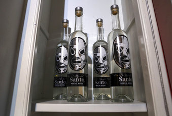 En esta fotografía del 28 de julio de 2017, varias botellas de mezcal El Santo son exhibidas en una de las tres tiendas que venden diversos artículos relacionados con el famoso luchador, en la Ciudad de México. El Santo se convirtió en un ídolo popular entre los mexicanos y algunos turistas. (AP Foto/Gustavo Martínez Contreras)