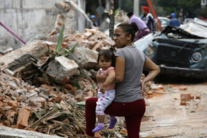 Una mujer y su hijo observan sobre escombros de edificaciones colapsadas después de un terremoto en Juchitan, Oaxaca, México, (AP Photo/Marco Ugarte)