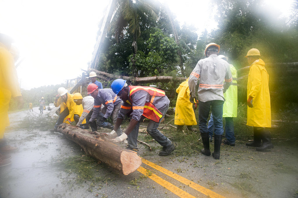 Empleados de una compañía eléctrica en Sánchez, quitan escombros de una vía tras el paso del huracán Irma. (AP Photo/Tatiana Fernandez)