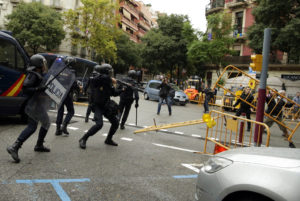 Un policía antidisturbios dispara una bala de goma hacia personas que tratan de llegar a un sitio de votación en una escuela en Barcelona, ​​España, para participar en el referendo independentista Cataluña que Madrid considera ilegal, el 1 de octubre de 2017. (AP Photo/Manu Fernandez)