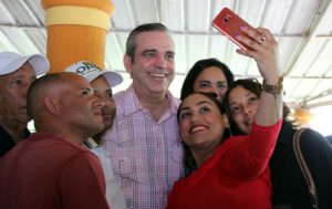 Una joven toma una selfie con Luis Abinader y otras personas.