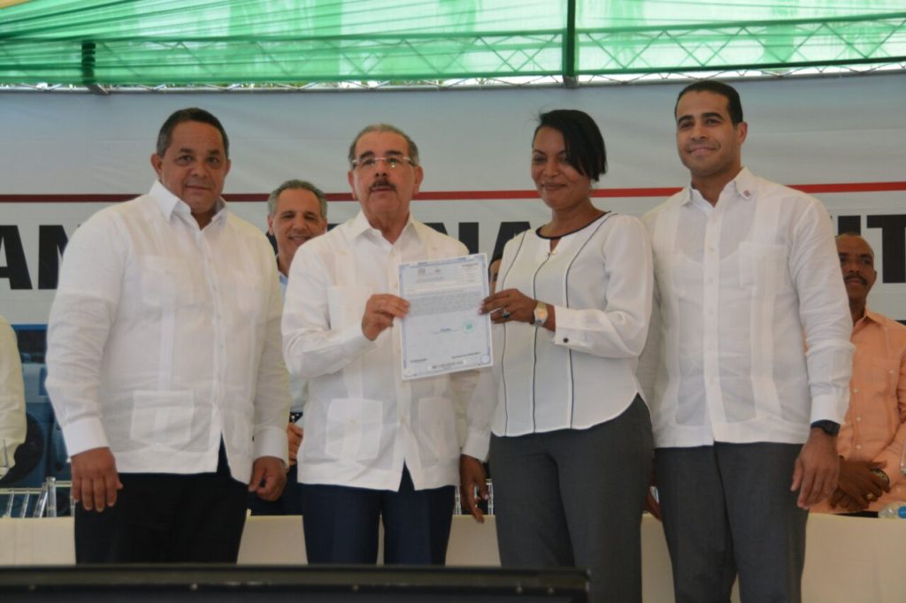 El presidente Danilo Medina al momento de entregar títulos definitivos a familias en Villa Altagracia