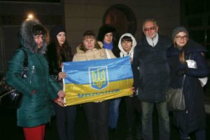Familiares y amigos de soldados ucranianos capturados por las fuerzas rebeldes sostienen una bandera ucraniana en momentos en que esperan por un canje de prisioneros en el aeropuerto de Kiev en Ucrania el 27 de diciembre del 2017. (AP Photo/Efrem Lukatsky)