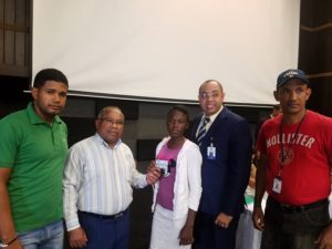 Príamo Rivas, junto a José Enrique Genao, funcionario del MESCyT, entregan a la estudiante de Biología y Química Cristy Alondra Urbáez, su tarjeta de débito. A la derecha el presidente de la FED, bachiller Randy Santana y el dirigente estudiantil Rafael Rodríguez