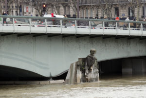 En esta fotografía del jueves 25 de enero de 2018, la gente camina sobre el puente del Alma a la altura de la estatua Zouave, la cual sirve como un instrumento de medición durante las inundaciones en París. (AP Foto/Christophe Ena)