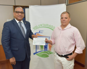 El gerente del Banco Central y presidente del Voluntariado Bancentraliano, Ervin Novas Bello, entrega el cheque de un millón de pesos a Sandy Herrera, padre de Andy