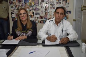 Iris Guaba, directora del Plan Social y el doctor Antonio Cruz Jiminián mientras firman el acuerdo..