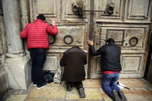 ARCHIVO - En esta imagen del domingo 25 de febrero de 2018, visitantes que rezan ante las puertas de la Iglesia del Santo Sepulcro, donde según la tradición cristiana fue sepultado Jesús, en Jerusalén. (AP Foto/Mahmoud Illean, Archivo)