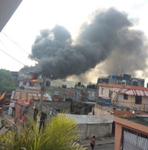 El humo producto del incendio que afecta un taller de ebanistería en Los Tres Brazos, se ve a distancia.