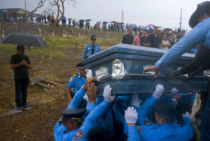 En esta fotografía del 29 de septiembre de 2017 se muestra a la policía levantar un ataúd de un elemento que murió durante el paso del huracán María en Aguada, Puerto Rico. (AP Foto/Ramon Espinosa, Archivo)