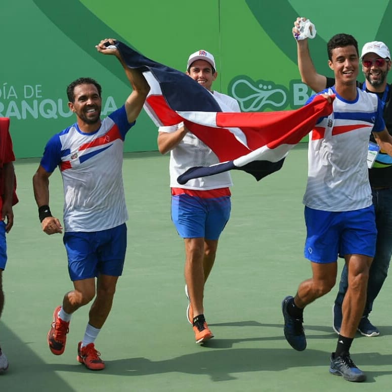 Los tenistas Víctor Estrella y Roberto Cid recorren la cancha con la bandera dominicana tras ganar oro en dobles en Centroamericanos