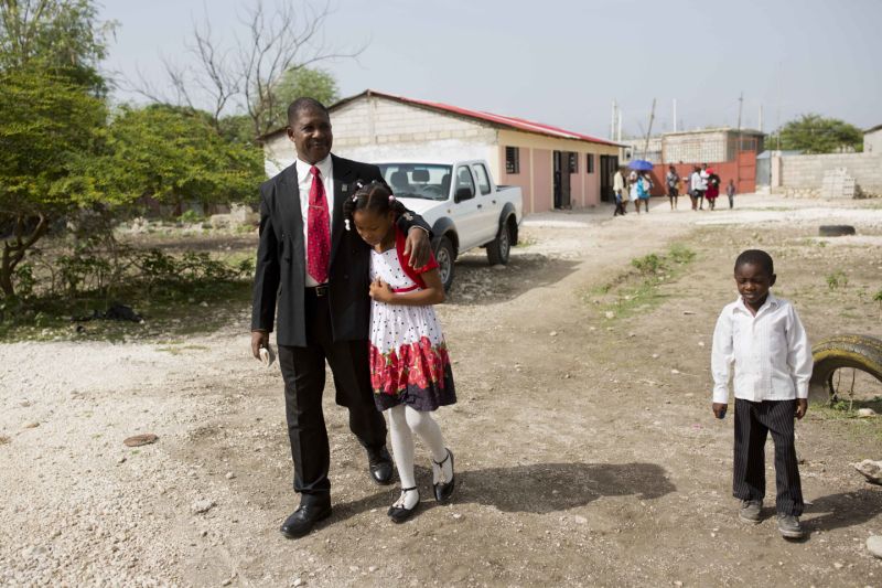 El pastor Jeannes Pierre camina con su hija adoptiva Franchina, de 11 años, después de una misa en una iglesia bautista de Puerto Príncipe el 1ro de julio del 2018. (AP Photo/Dieu Nalio Chery)