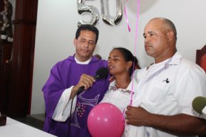 Los padres de Emely Peguero junto al párroco Diómedes Antonio Ángeles en misa por primer aniversario del crimen de la adolescente.
