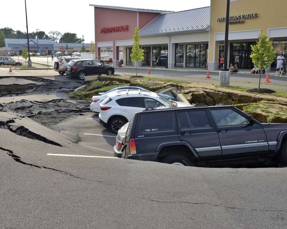 Varios vehículos permanecen en un socavón que se abrió en un estacionamiento del centro comercial Tanger Outlets en Lancaster, Pensilvania, (Blaine T. Shahan /LNP/LancasterOnline vía AP)