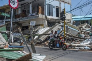 Dos hombres en una motocicleta pasan junto a construcciones arruinadas por el terremoto del domingo en Pamenang, en la isla de Lombok, Indonesia, el viernes 10 de agosto de 2018. (AP Foto/Fauzy Chaniago)