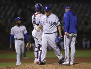 El lanzador dominicano Bartolo Colón, centro, de los Rangers de Texas, abandona el montículo tras ser relevado por el manager Jeff Banister, derecha, en el sexto inning de un juego de béisbol contra los Atléticos, el lunes 20 de agosto de 2018, en Oakland, California. (AP Foto/Ben Margot)