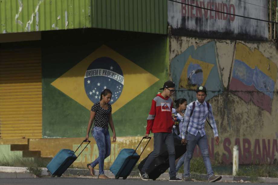 En esta fotografía de archivo del 9 de marzo de 2018, unos venezolanos avanzan con su equipaje tras cruzar la frontera entre Brasil y Venezuela en la ciudad de Pacaraima, en el estado brasileño de Roraima. (AP Foto/Eraldo Peres).