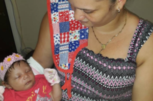 Yesenia García carga su bebé para la que pide ayuda.