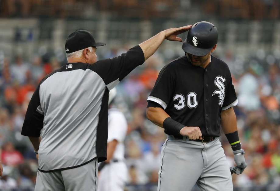 El mánager Rick Rentería, derecha, de los Medias Blancas de Chicago, da un ligero golpe en la cabeza a Nicky Delmonico (30), que recibió un pelotazo, en el duelo ante los Tigres en Detroit, el lunes 13 de agosto de 2018. (AP Foto/Paul Sancya)