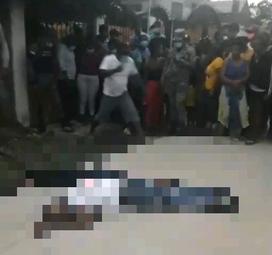 Curioros observan los cadáveres de dós jóvenes asesinados en Barahona.